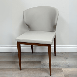 Light grey upholstered dining chair with curved backrest and walnut veneer legs, suitable for restaurant or home use.