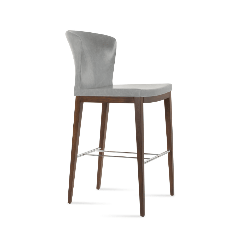 Grey upholstered counter height stool with winged back and dark wood legs