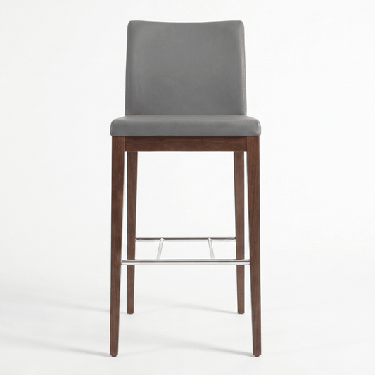 Aria Grey high back bar stool featuring upholstered seat, curved backrest, wooden legs, and chrome footrest
